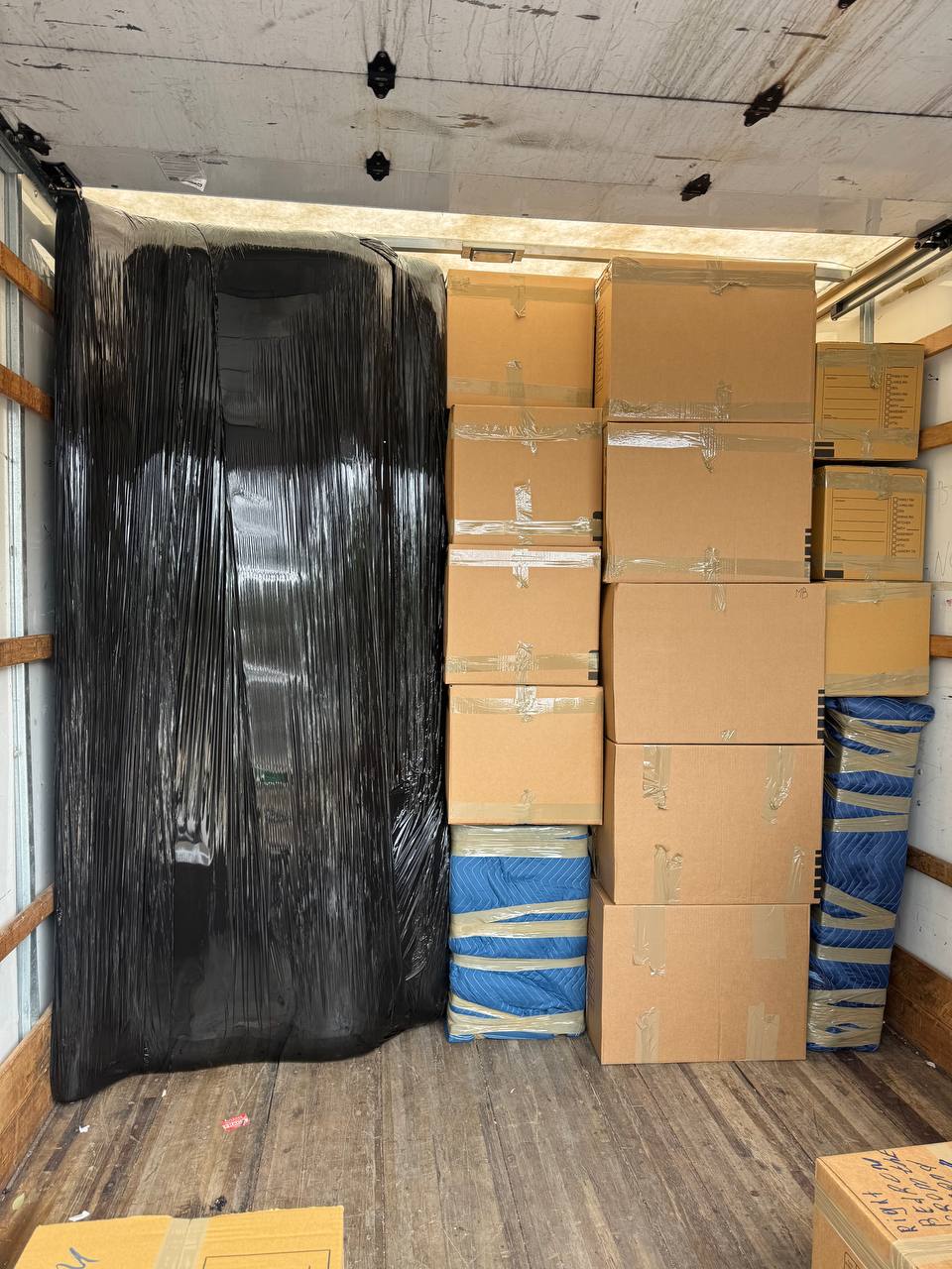 Moving truck interior packed with boxes and wrapped furniture